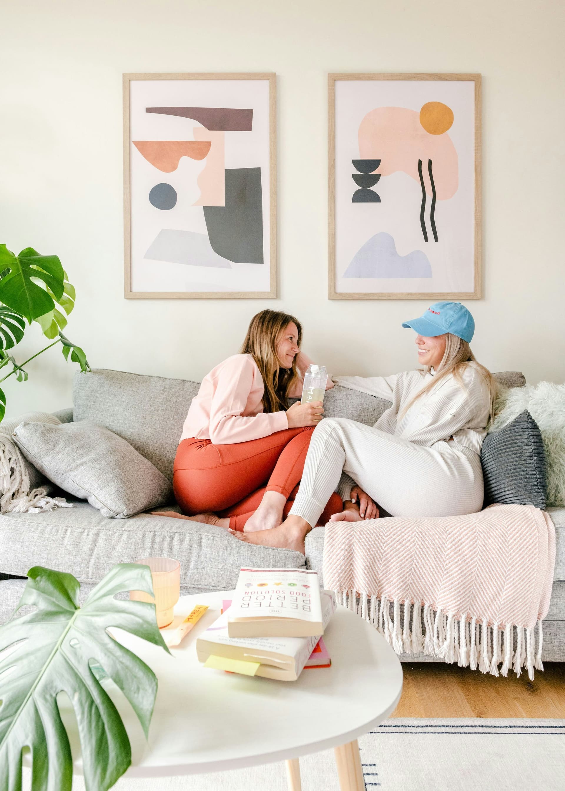 Zwei Frauen unterhalten sich entspannt auf einer Couch im Wohnzimmer
