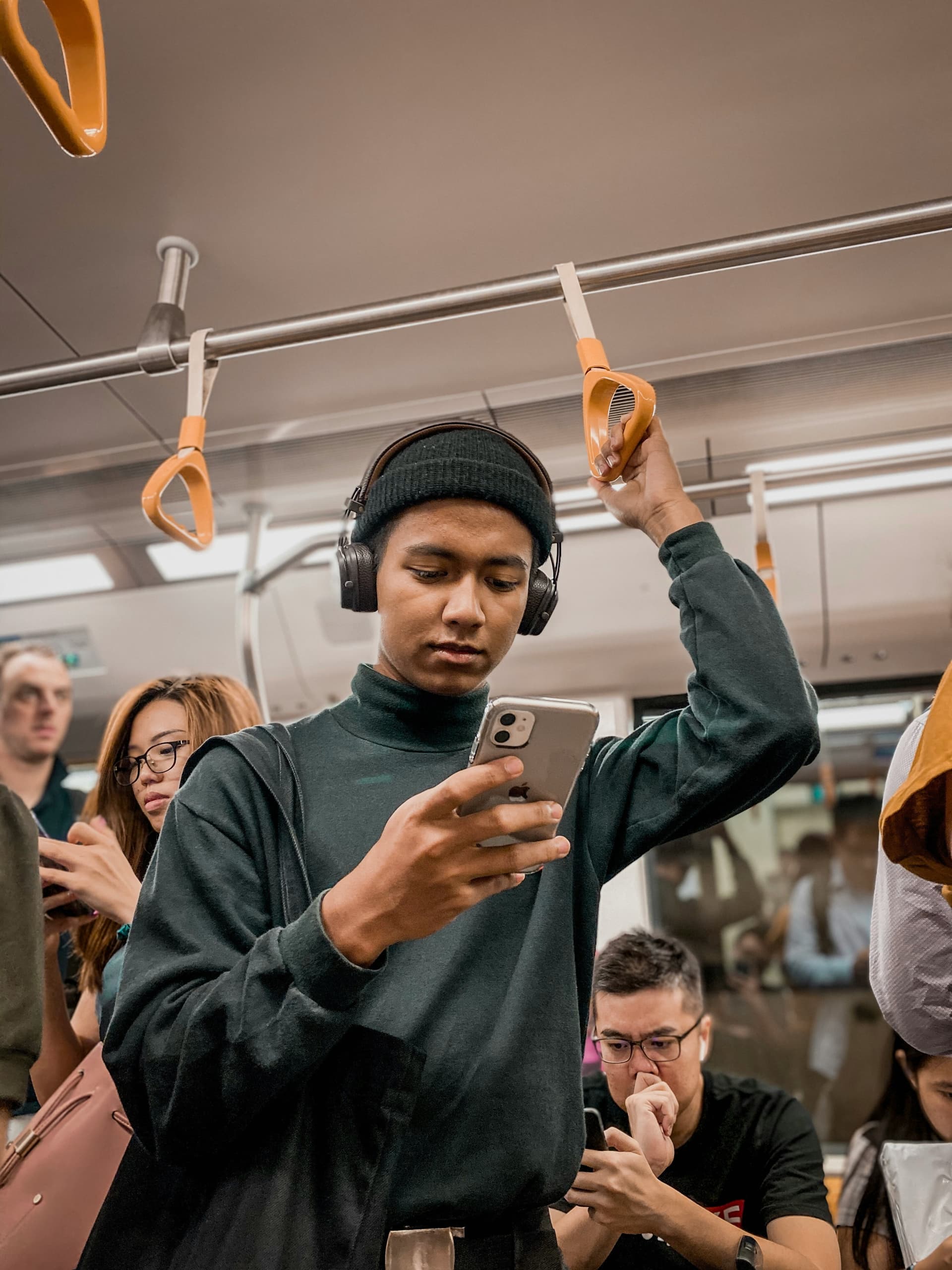 Person mit Smartphone in der U-Bahn, hält sich am Haltegriff fest