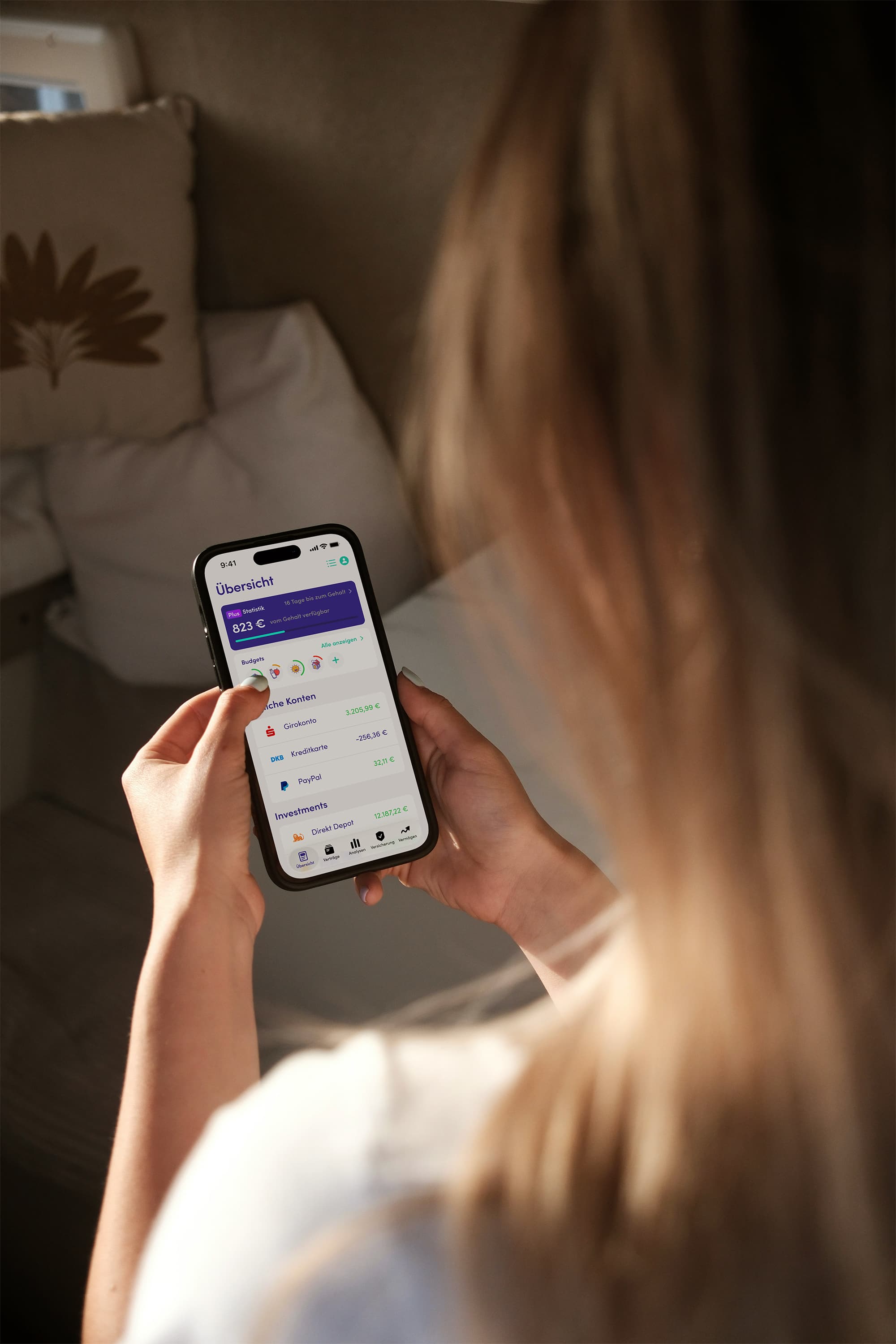 Person hält ein iPhone mit der Finanzguru App in der Hand